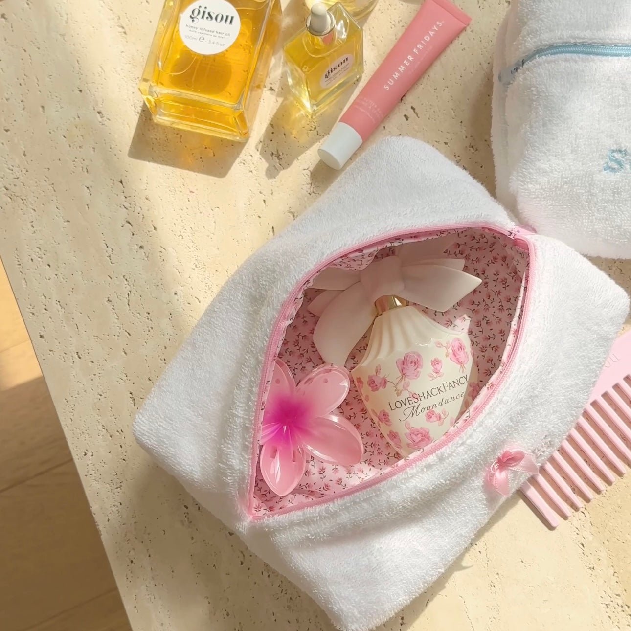 White plush pouch open to pink floral lining with bow and heart embellishment