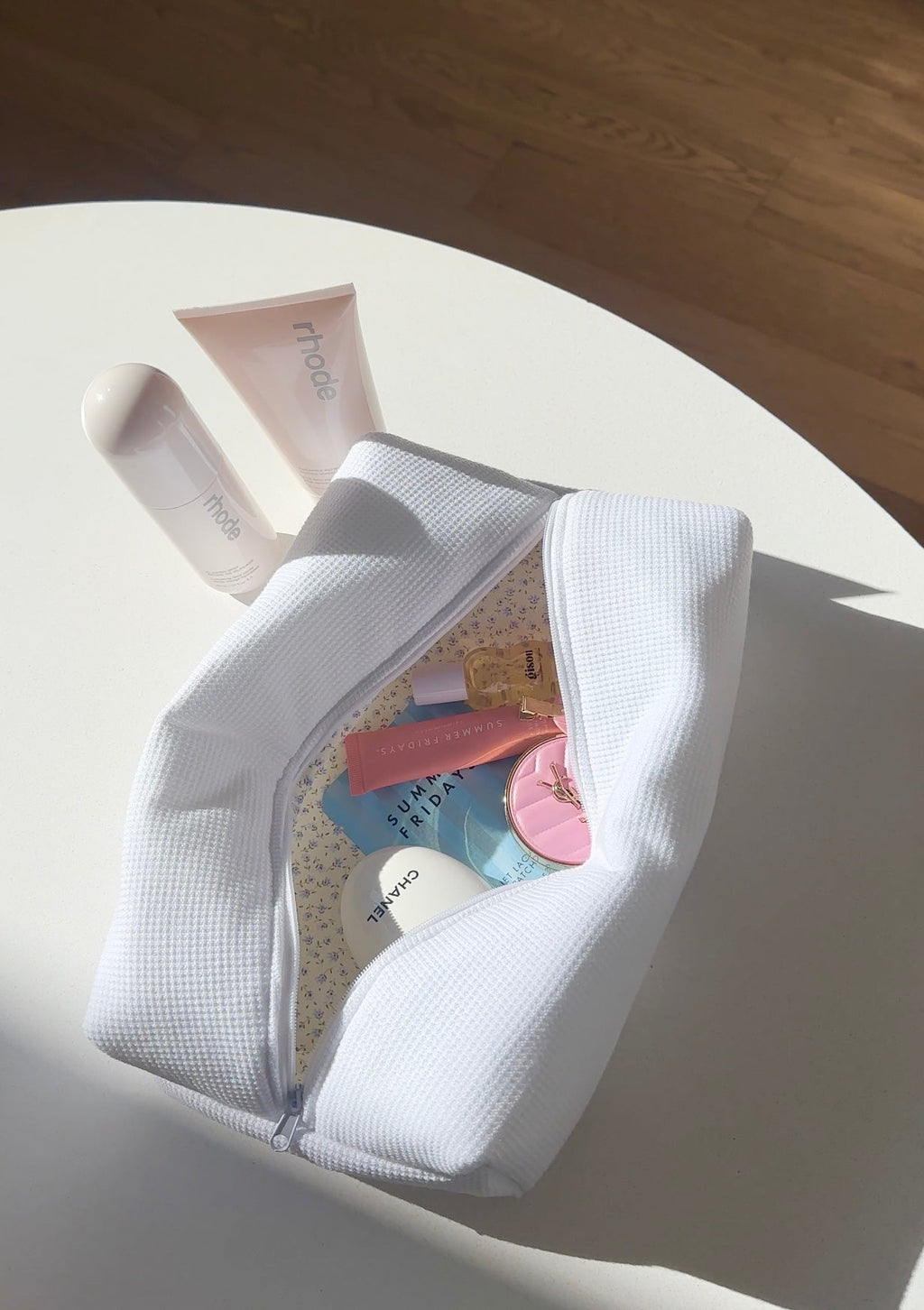 White waffle-knit zip pouch open with inner space and small items visible