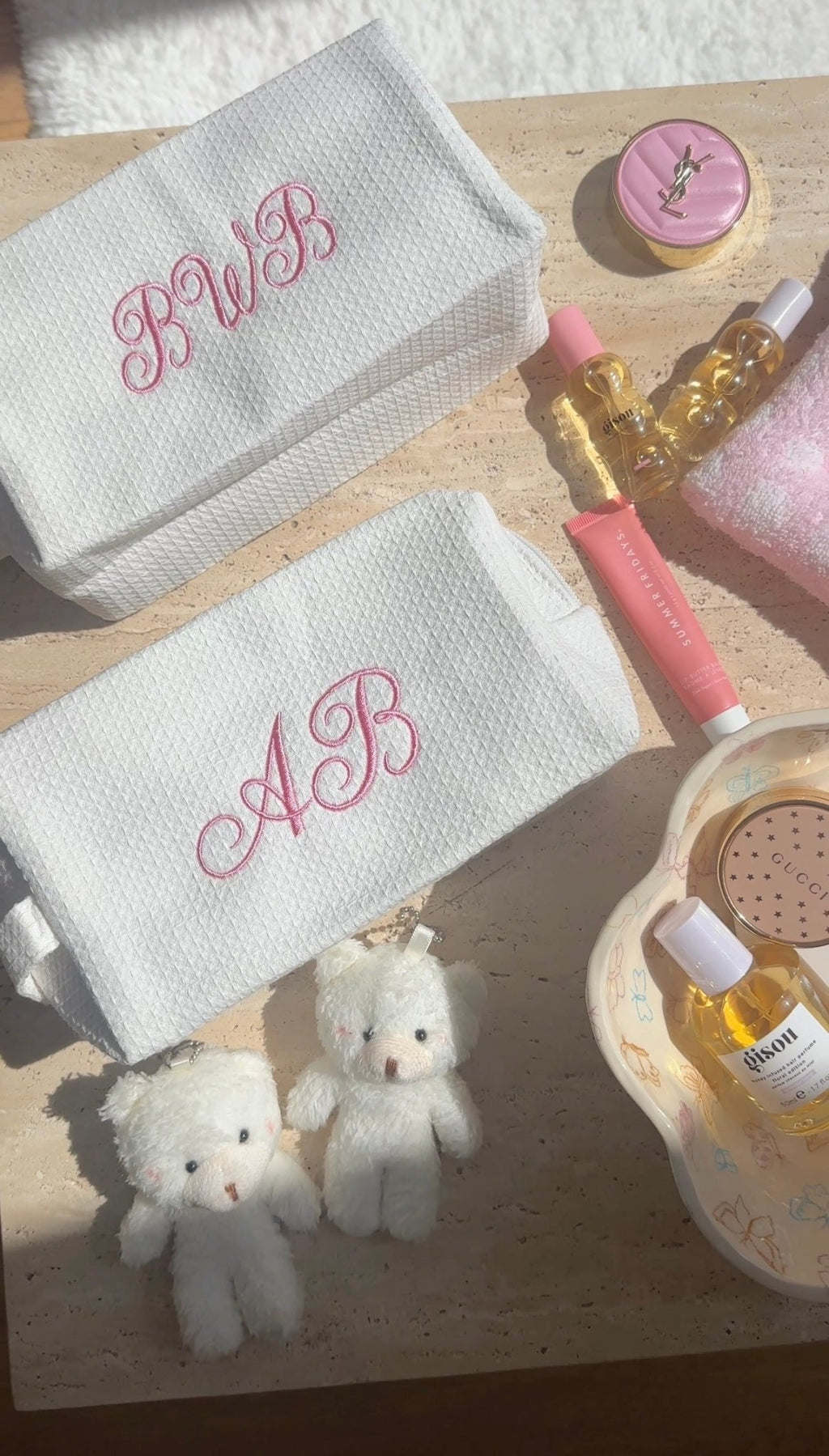 Two white waffle-knit custom embroidery pouches with pink embroidered initials