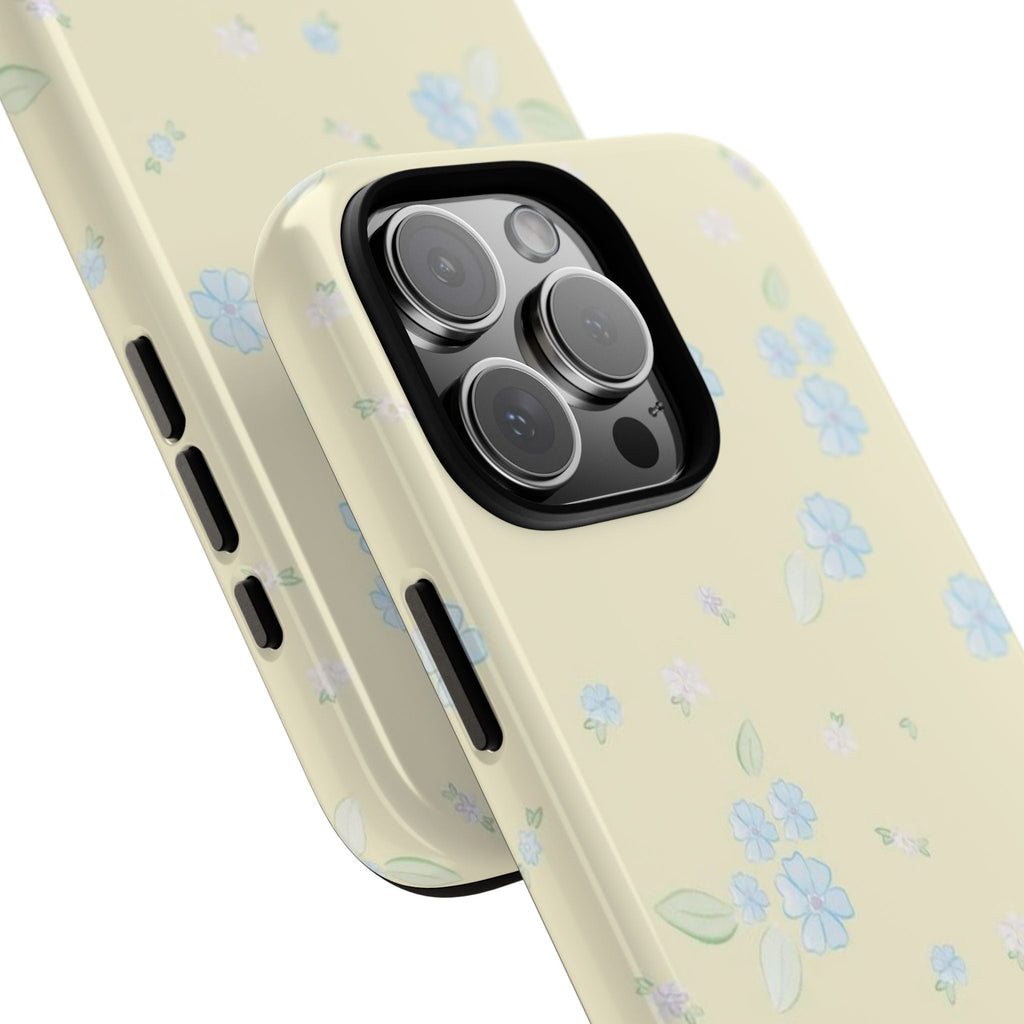Angled view: light yellow phone case with blue lily flowers and side button cutouts