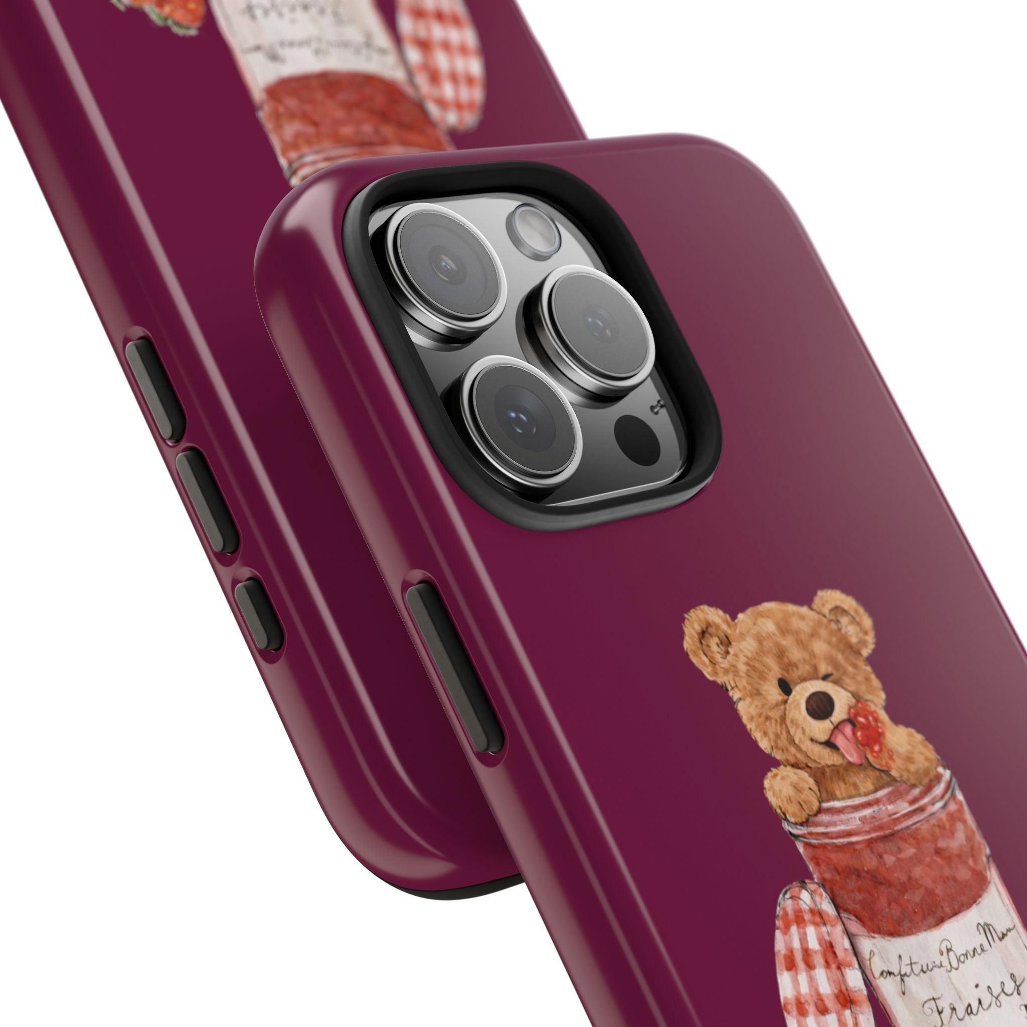 Close-up burgundy phone case with teddy jam-jar graphic beside camera lens cutouts