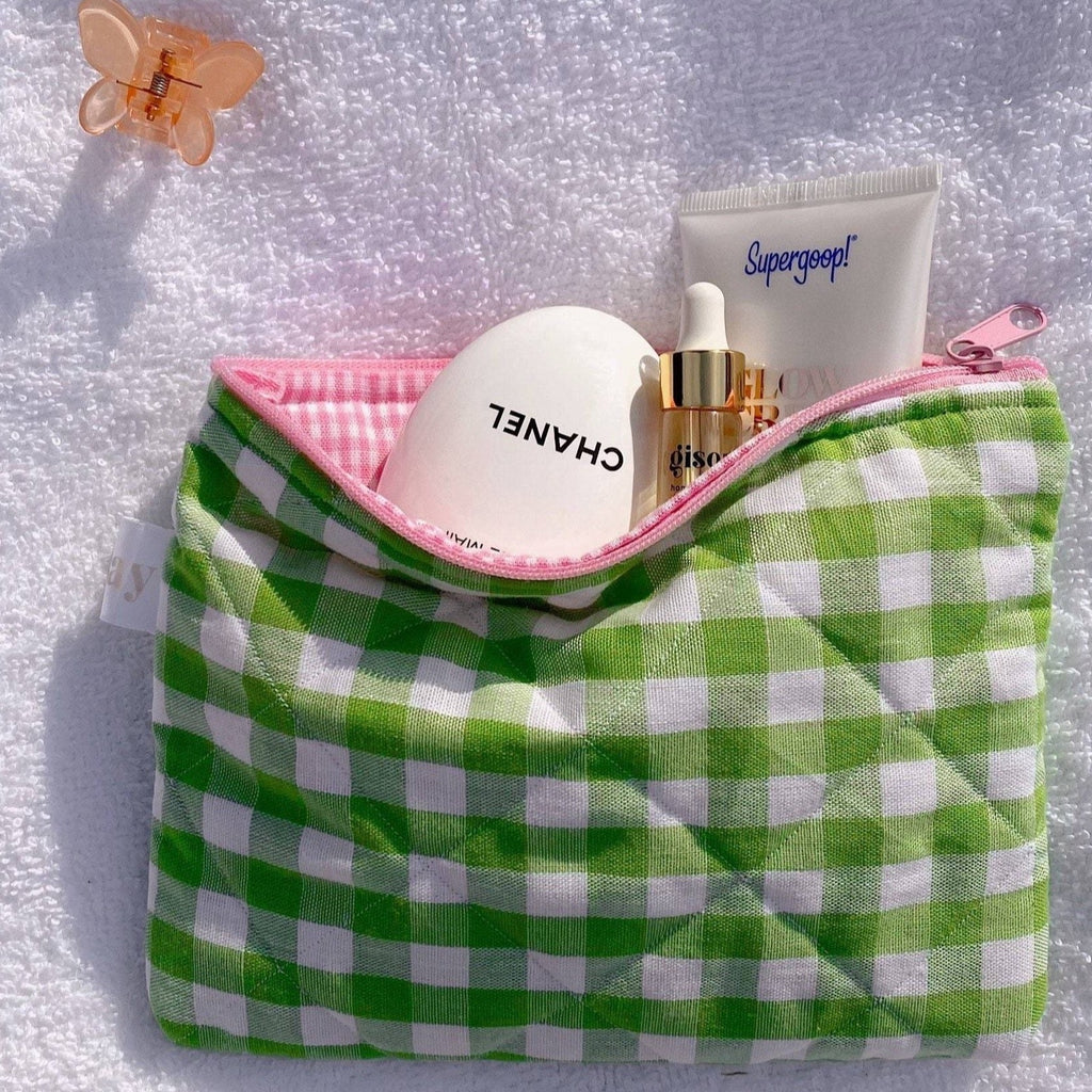 Green gingham toiletry pouch with pink zipper trim, round compact in view