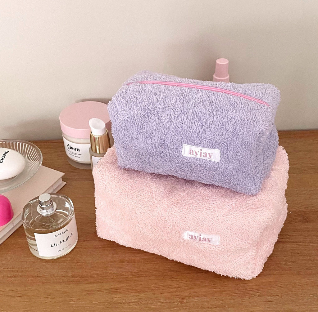 Pink teddy and fuzzy makeup bags stacked, both with rectangular zip fronts