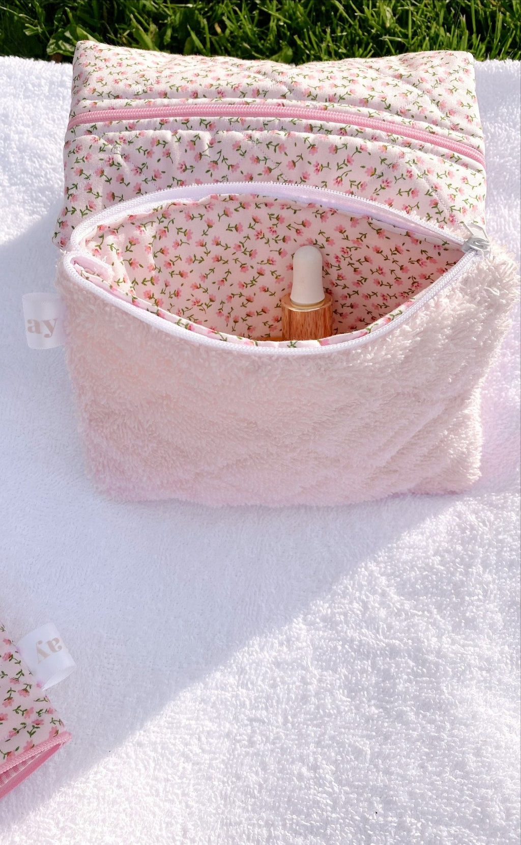 Baby pink teddy flat pouch open with pink zipper; floral lining and bottle