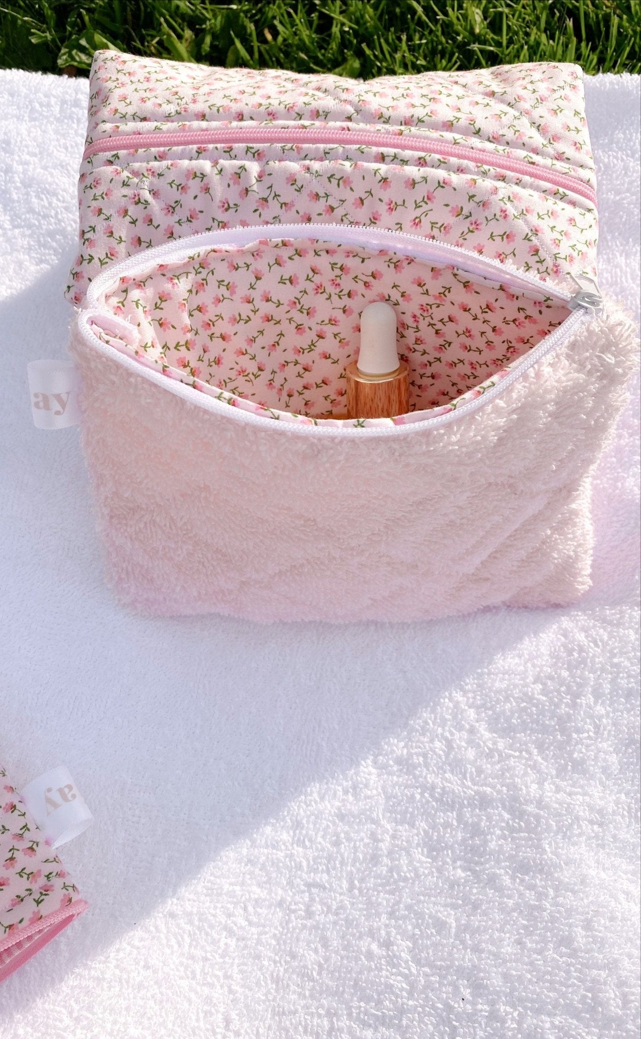 Baby pink teddy flat pouch open with pink zipper; floral lining and bottle