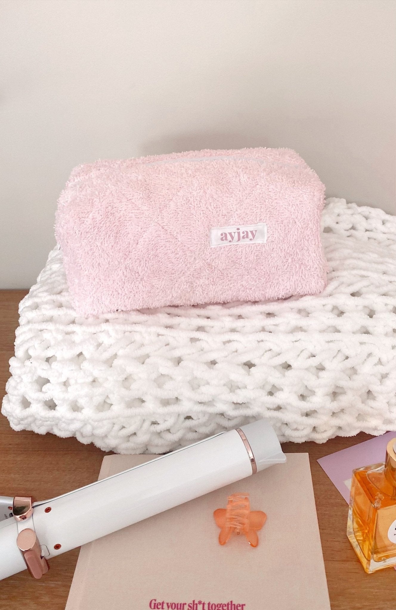 Baby pink teddy makeup bag with rectangular shape and stitched brand tag