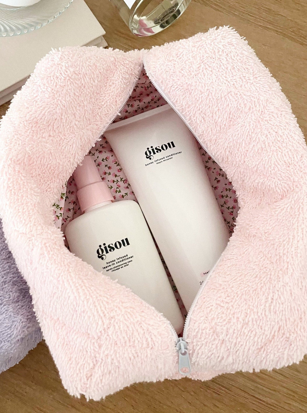 Open baby pink teddy makeup bag showing two white bottles and floral lining