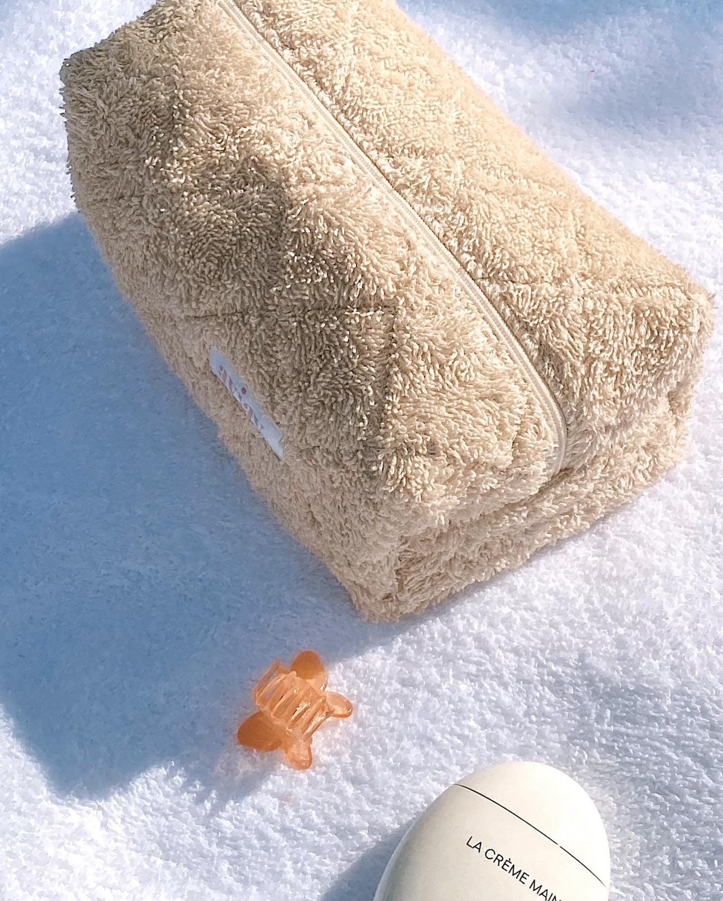 Beige terrycloth zip pouch with textured fabric and orange clasp