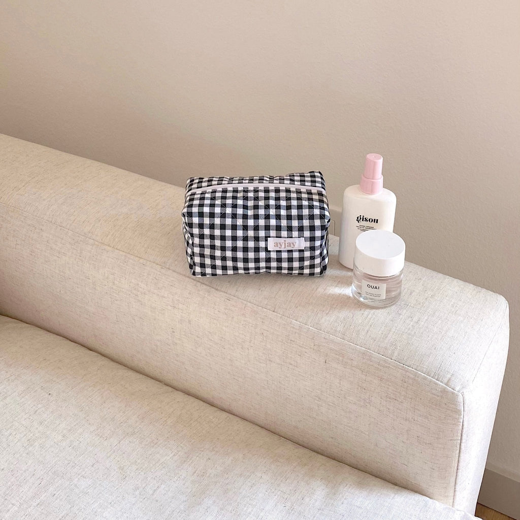 Black-and-white gingham zip pouch on couch; compact rectangular case