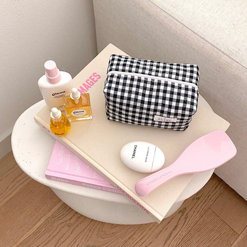 Black-and-white gingham zip pouch set on a tray; folded, compact rectangular shape