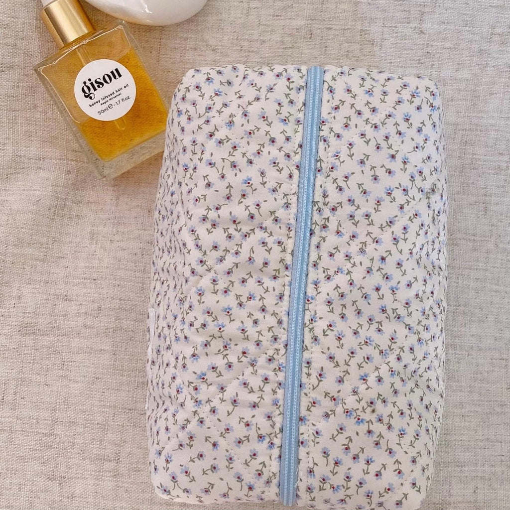 Blue ditsy floral pencil-style zip pouch, light-blue zipper centered, closed