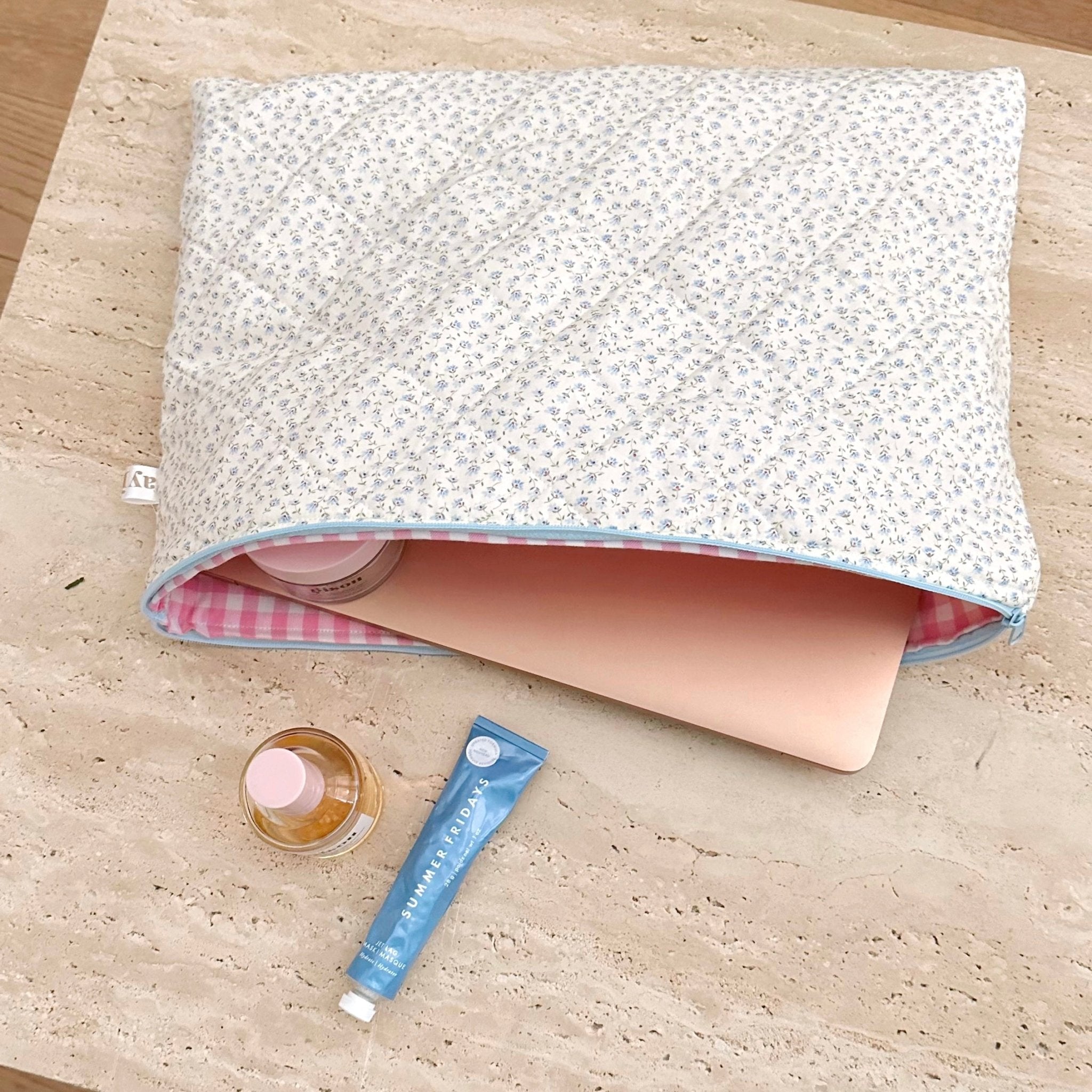 Blue ditsy floral cosmetic pouch opened, showing light pink interior and blue trim.
