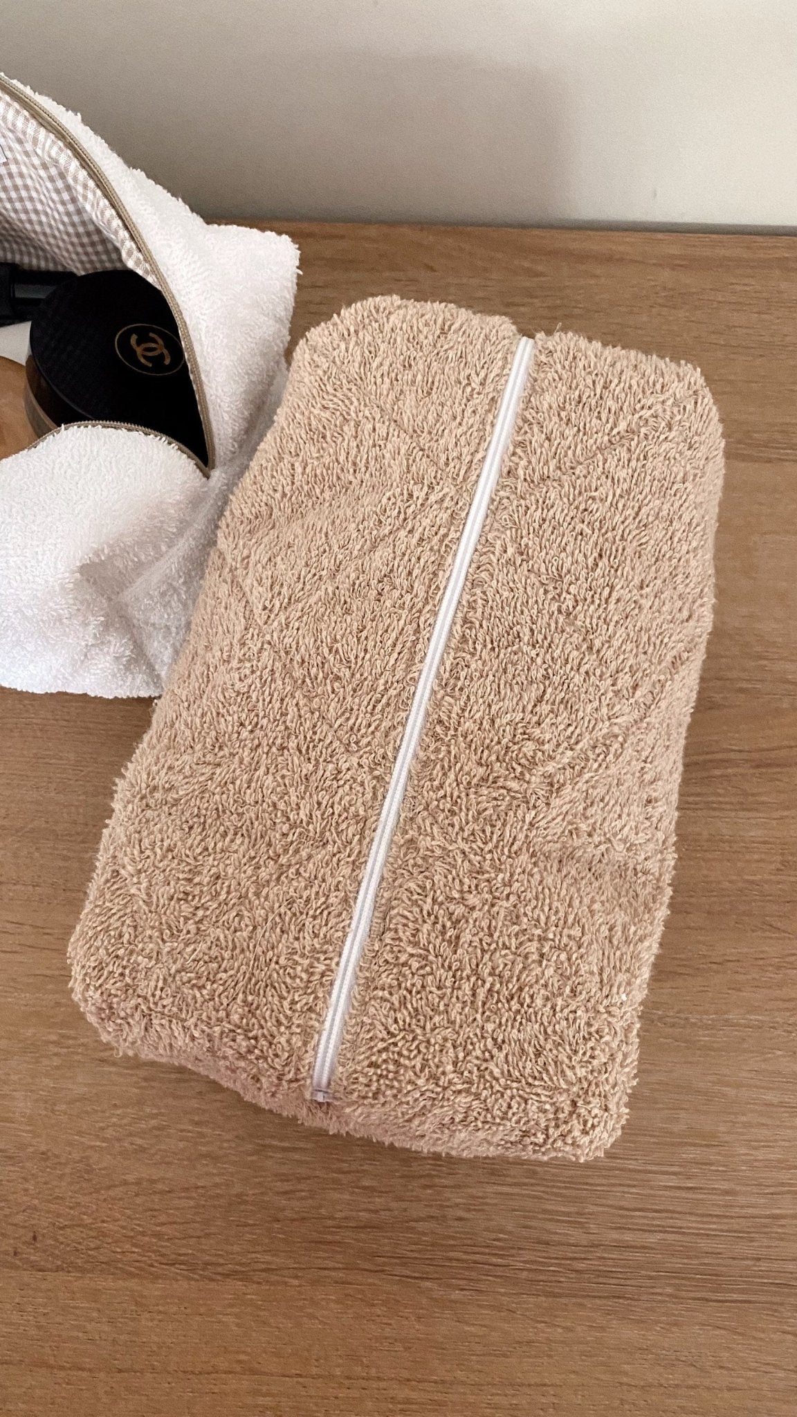 Brown teddy makeup pouch with white zip trim, shown closed and upright