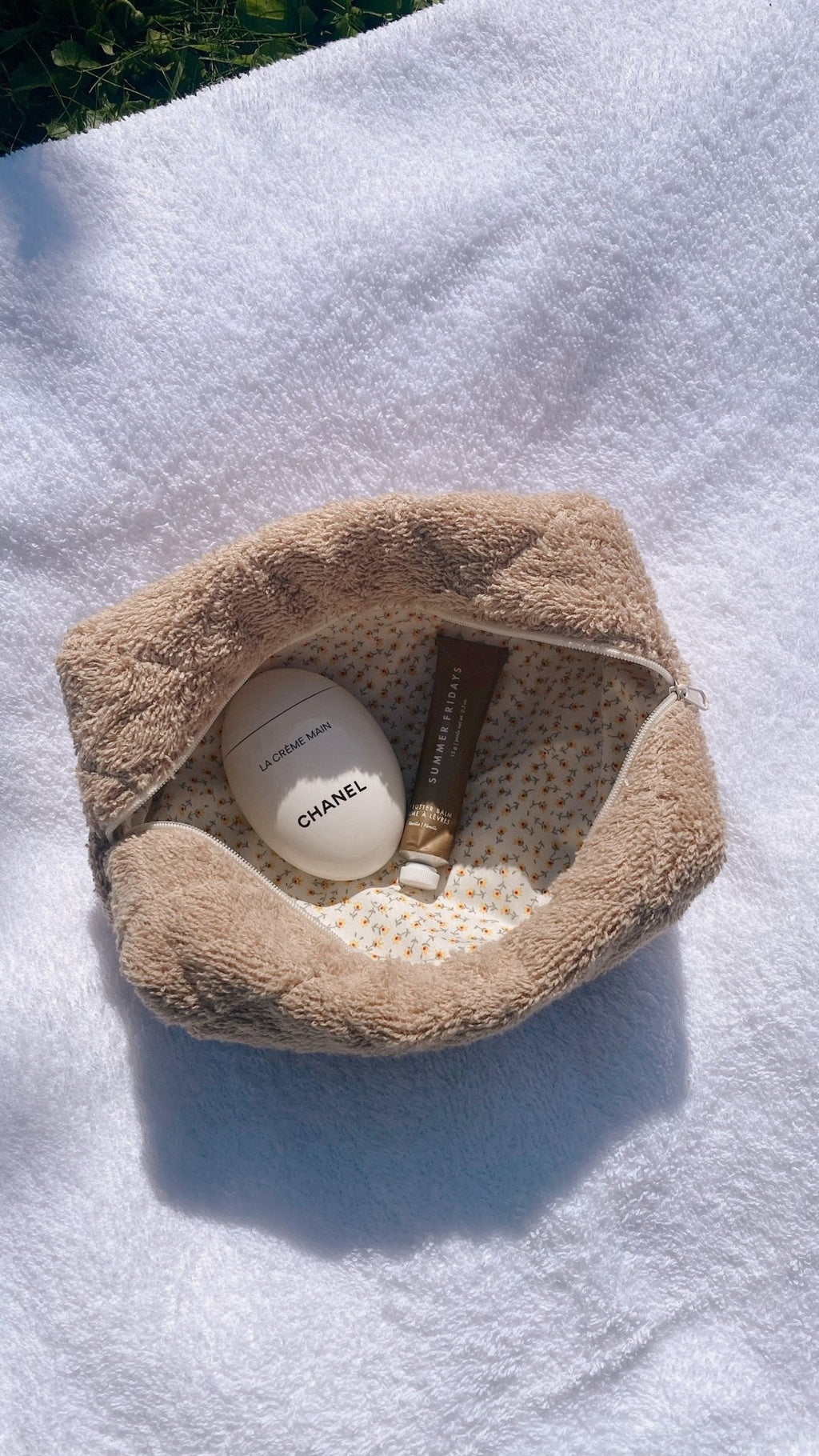 Beige terrycloth pouch opened wide, inner lining visible with bottles inside