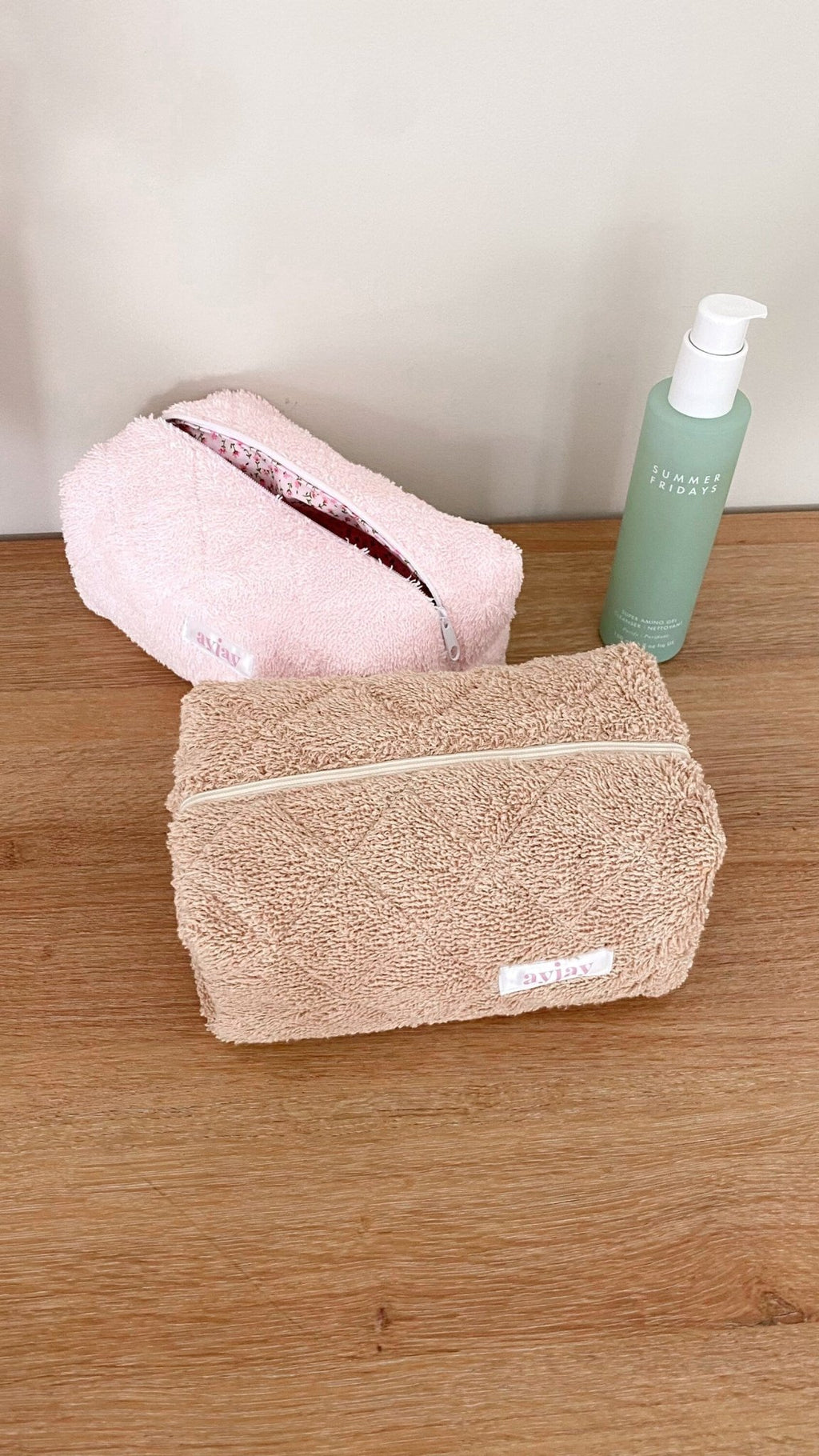 Beige terrycloth zip pouch with white trim, open top showing inner pouch lining