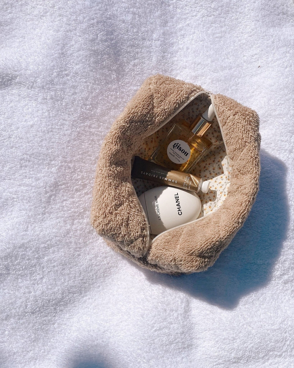 Tan terrycloth pouch opened flat, showing inner lining and toiletries inside