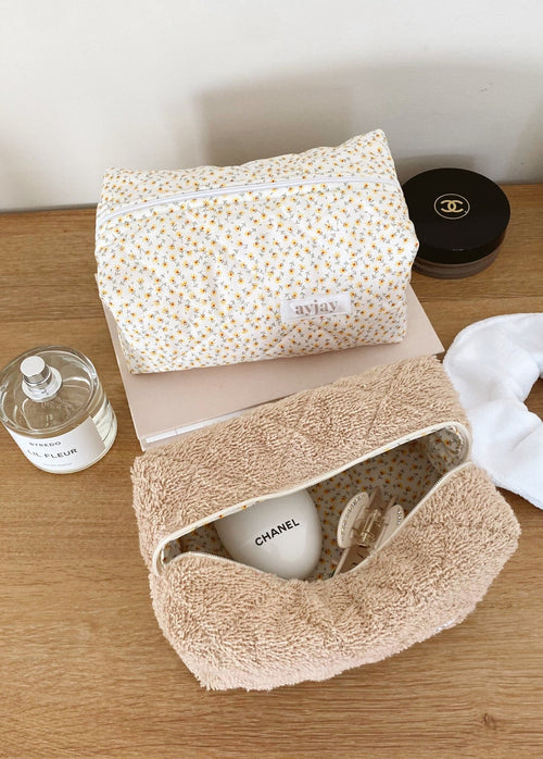 Cream terrycloth pouch with small yellow ditsy floral pattern, zip-top and label patch