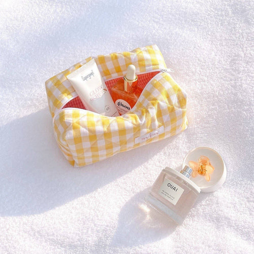 Butter yellow gingham zip pouch with rolled top, holding small bottles and a tube