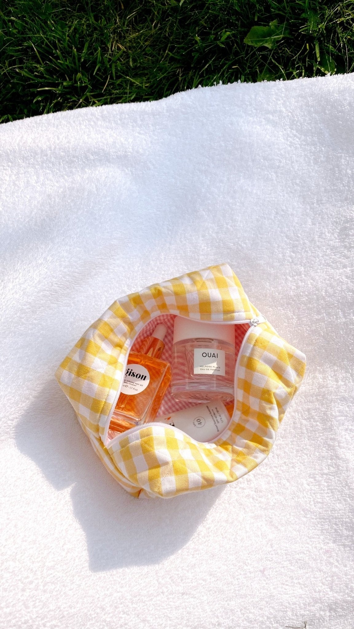 Butter yellow gingham pouch viewed from above, open with a clear bottle inside