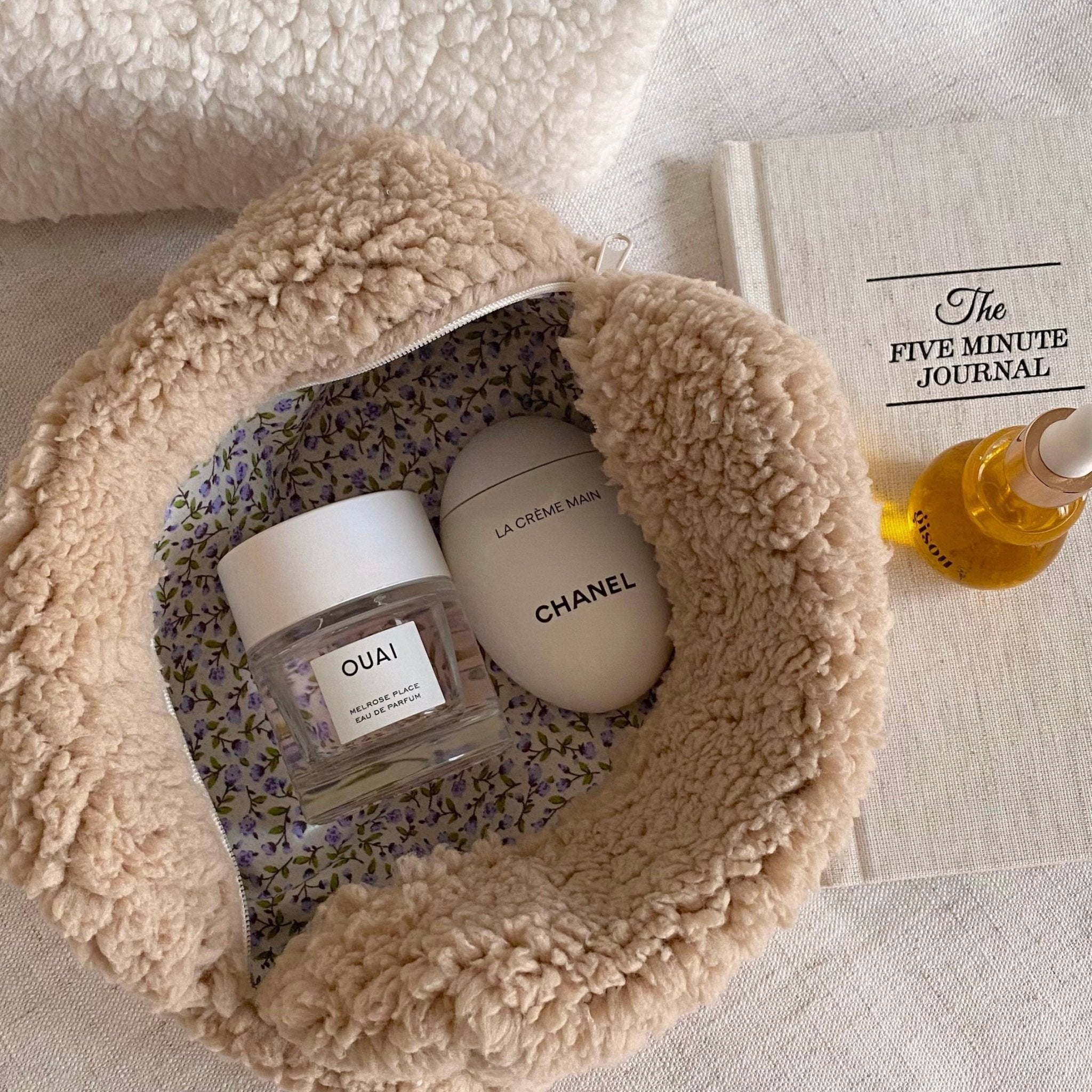 Camel soft teddy round zip pouch open to show lavender floral interior and product bottles.