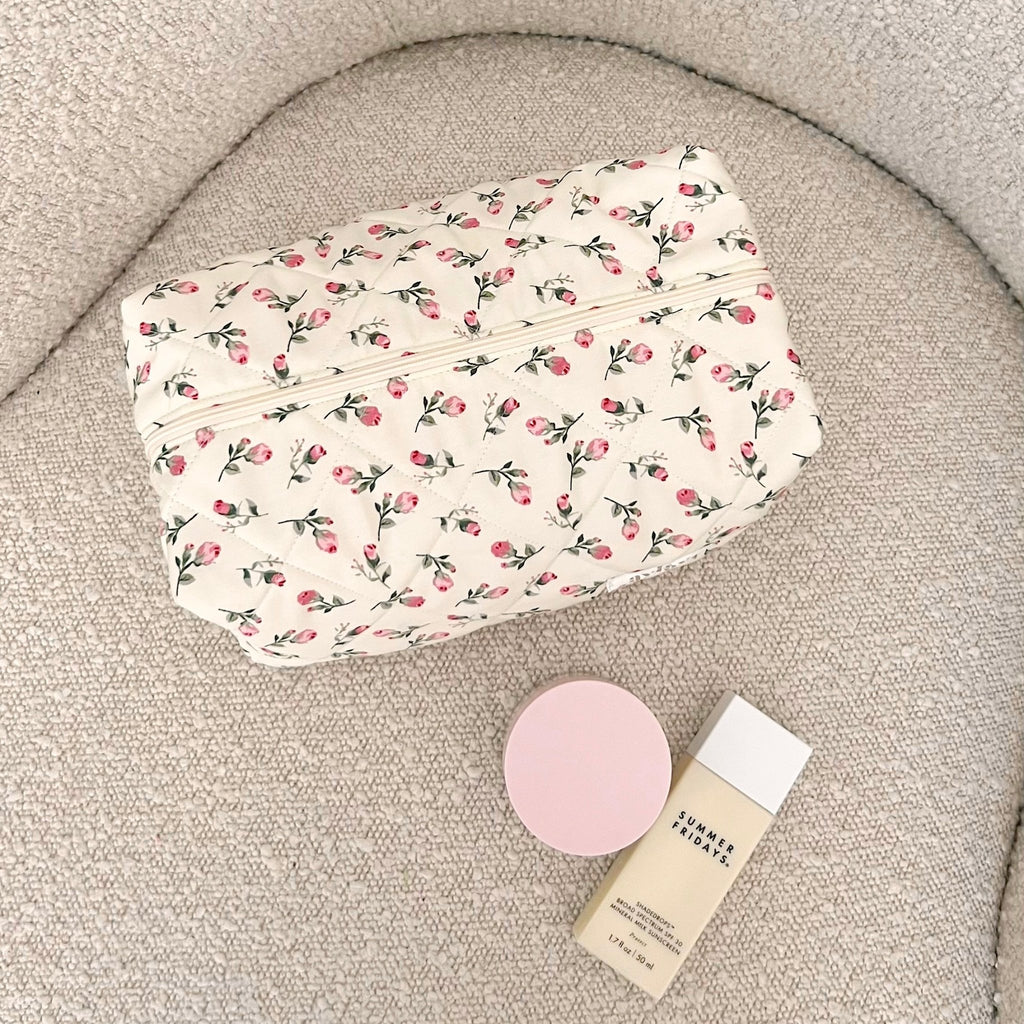 Cream floral zip pouch with pink trim, fully closed with curved zipper seam