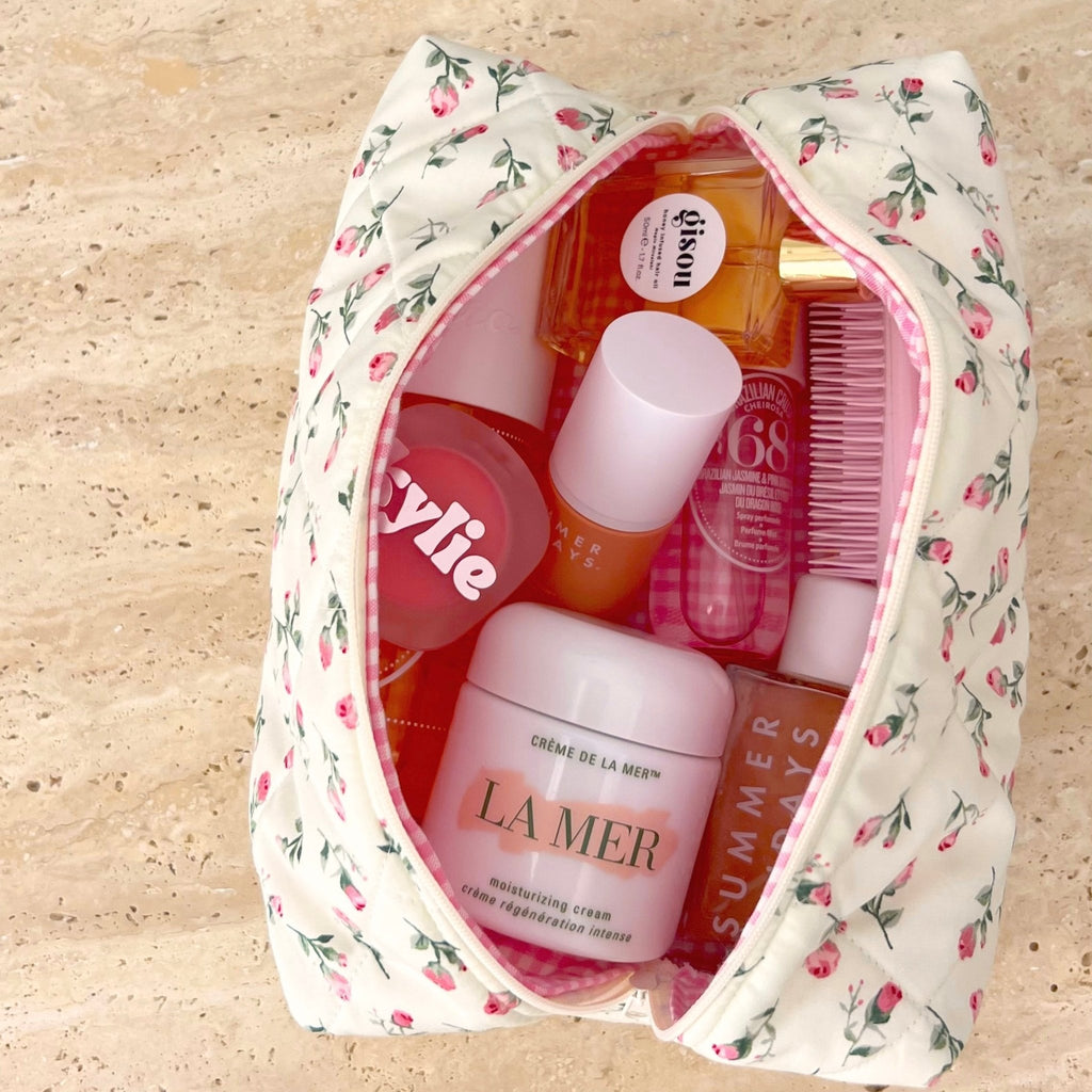 Cream floral cosmetic pouch with pink trim, open top showing toiletries inside