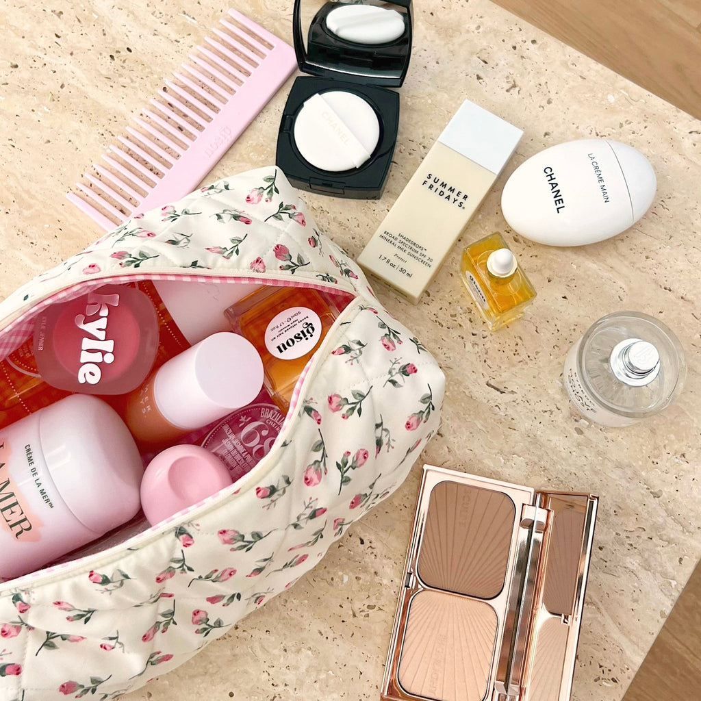 Cream floral cosmetic pouch with pink trim, open showing toiletries and refill items