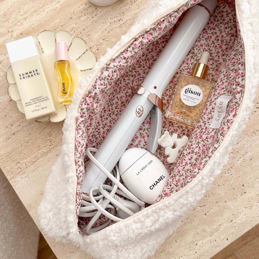 Cream soft teddy pouch with pink floral lining, open top showing interior items and cables