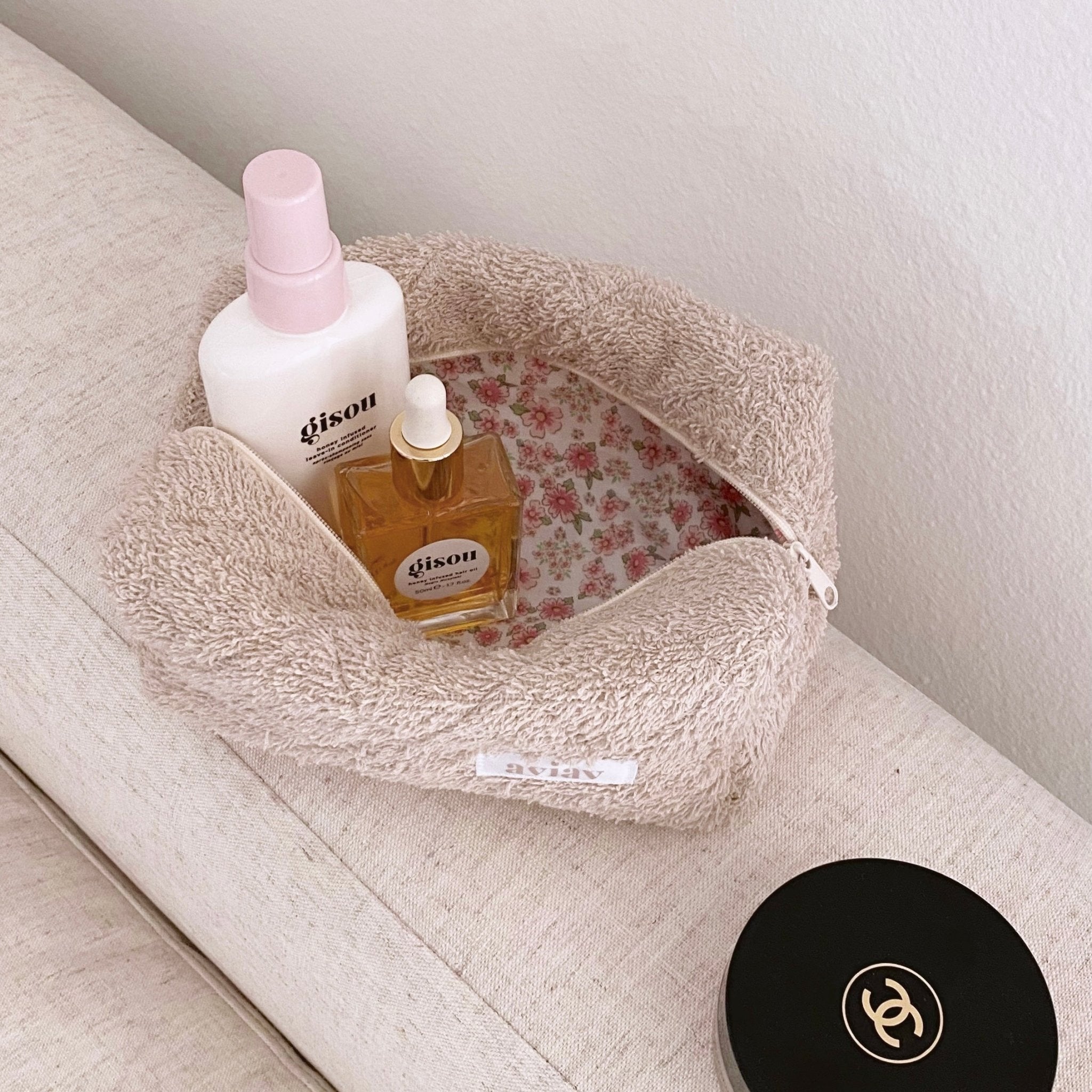 Beige teddy makeup bag with pink floral lining, top zipper, holds bottles inside