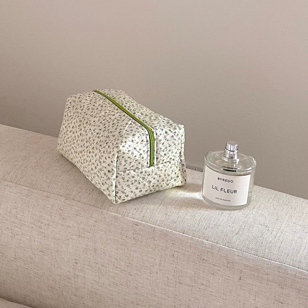 Compact green ditsy floral zip pouch with green piping, folded shape