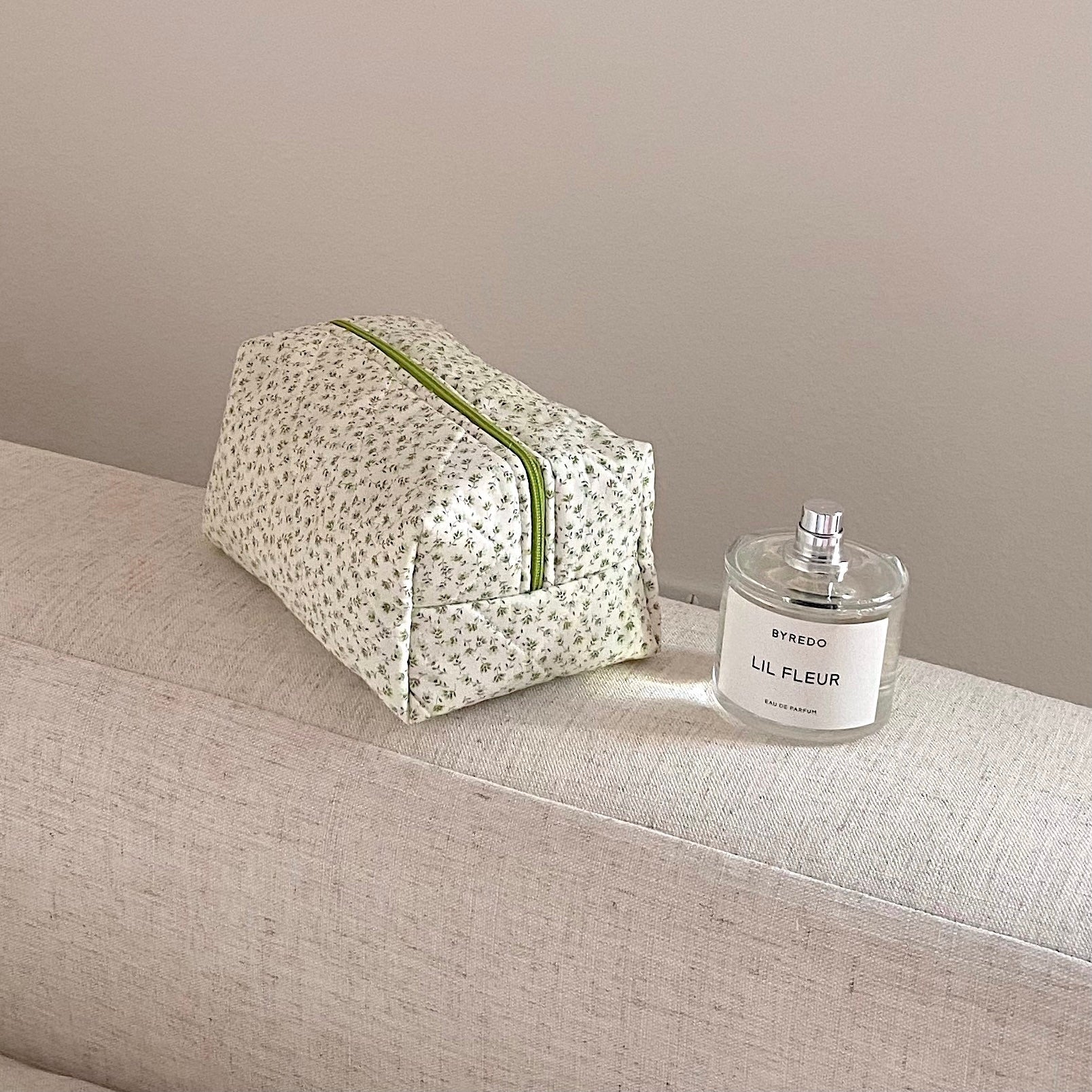 Compact green ditsy floral zip pouch with green piping, folded shape