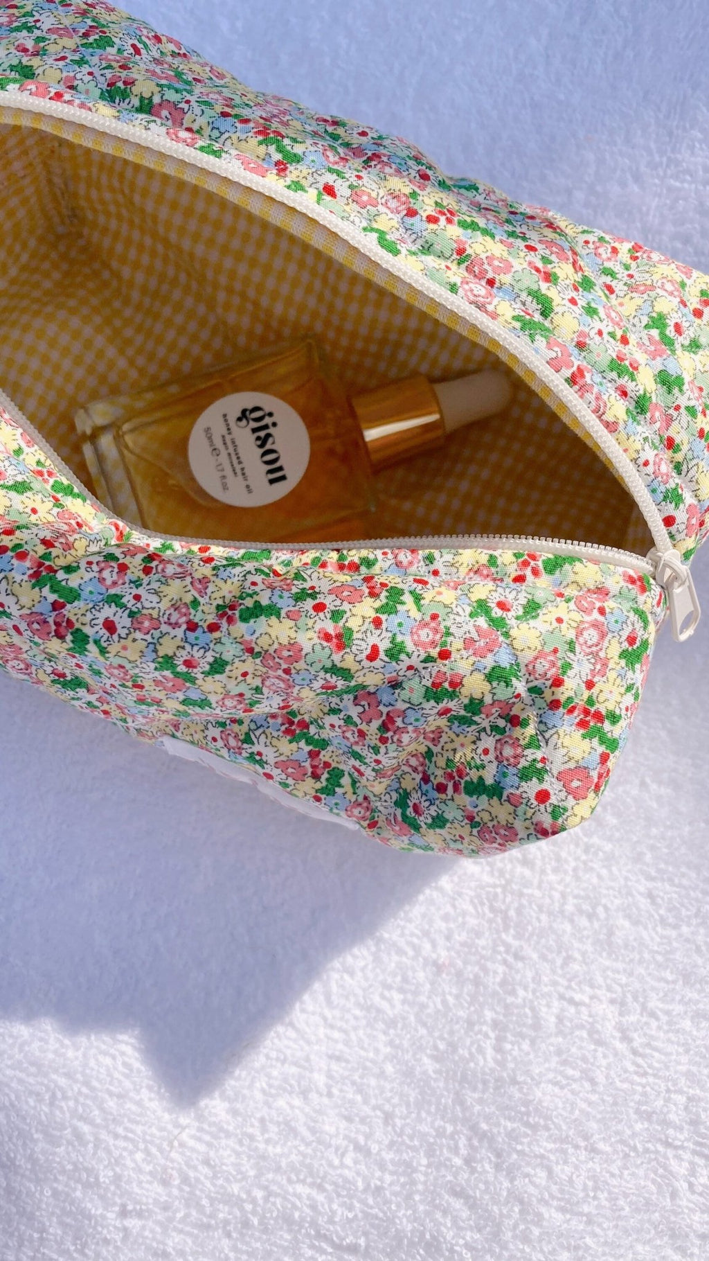 Close-up of floral zip pouch with yellow gingham lining and metal zipper pull