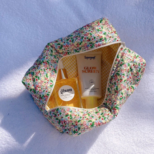 Floral zippered pouch bag open, showing interior with bottles and yellow lining