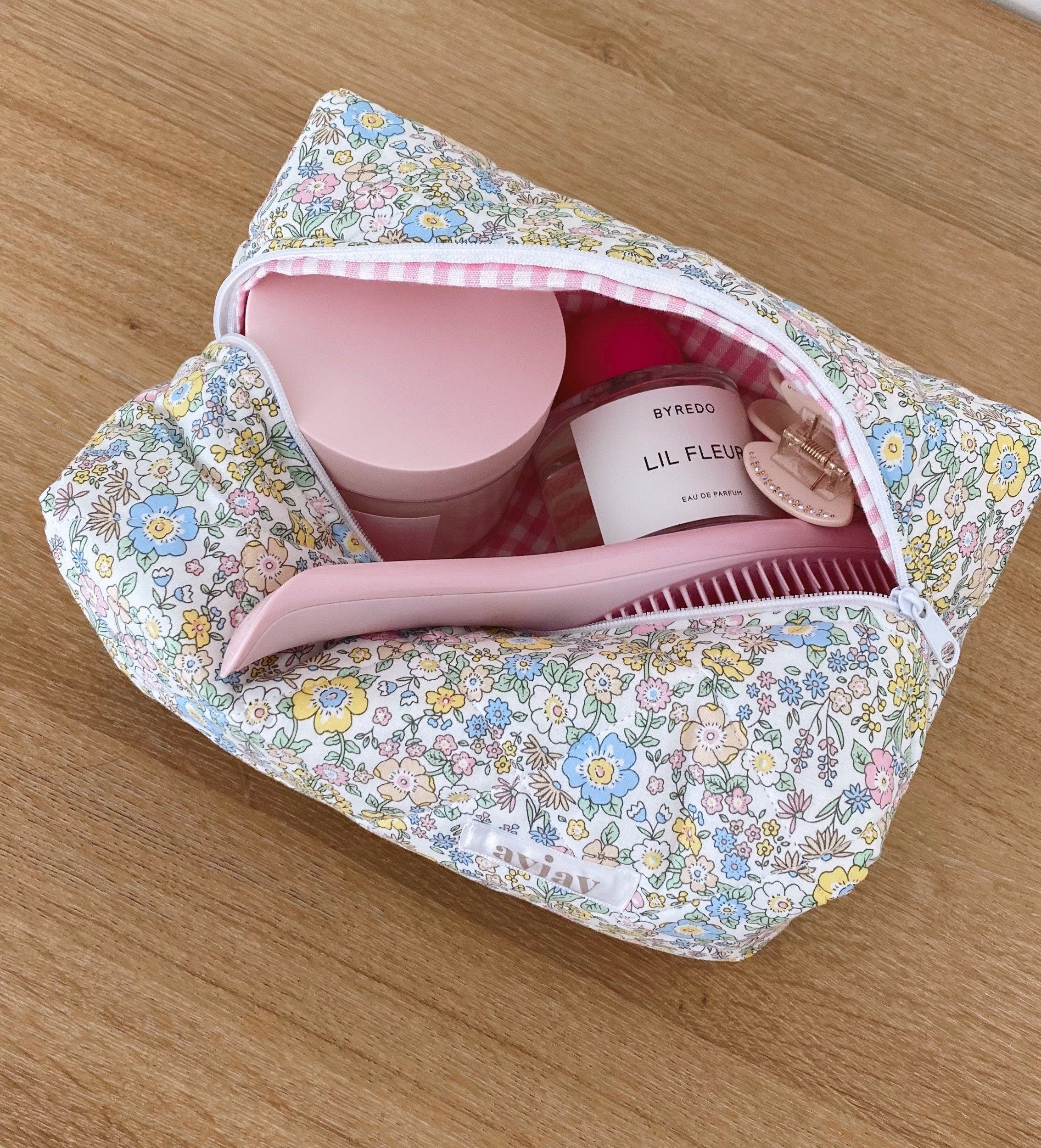 Pastel floral makeup bag open with pink interior and bottles tucked into pockets