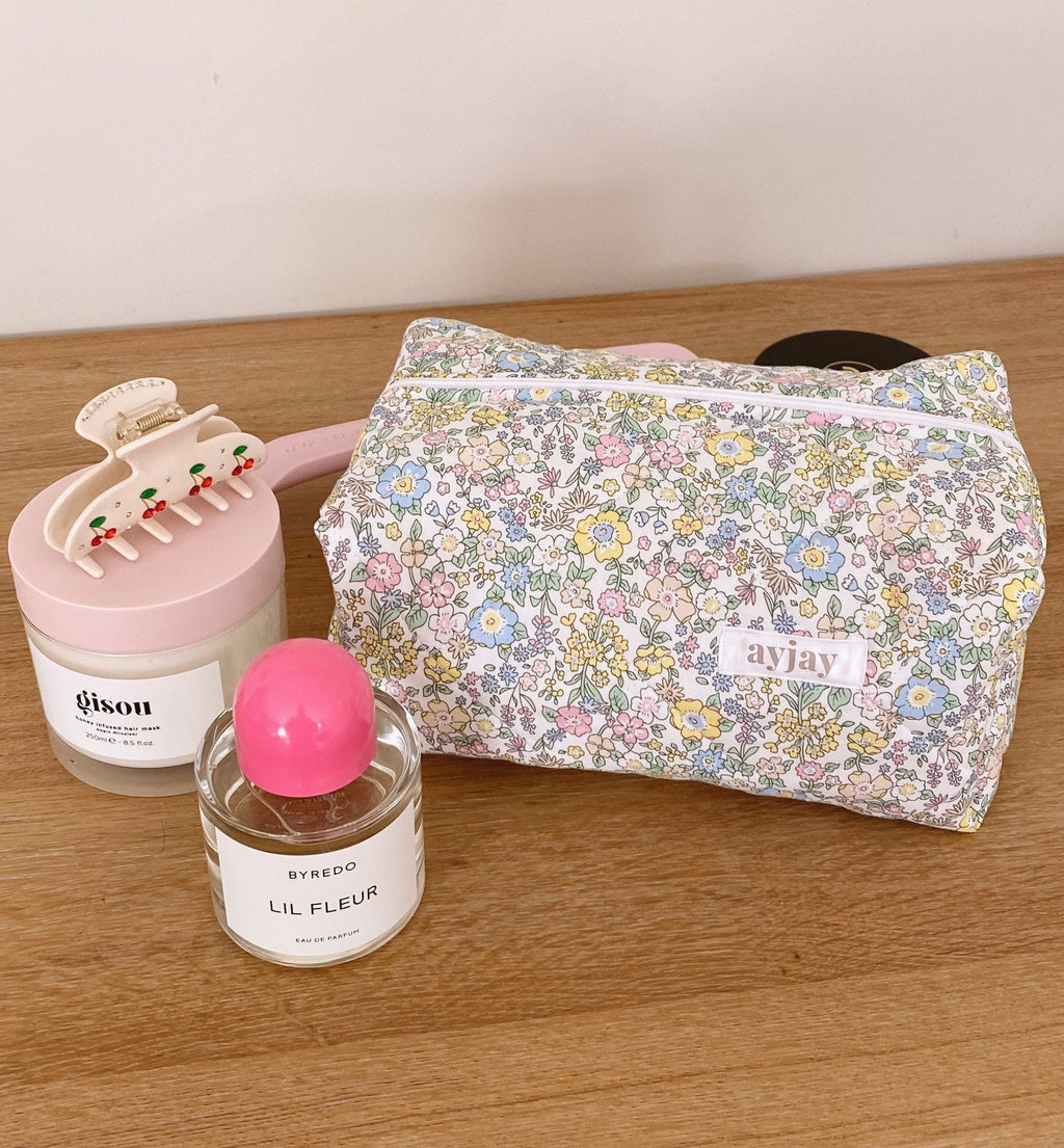 Pastel floral makeup bag closed with zipper and logo patch on the front