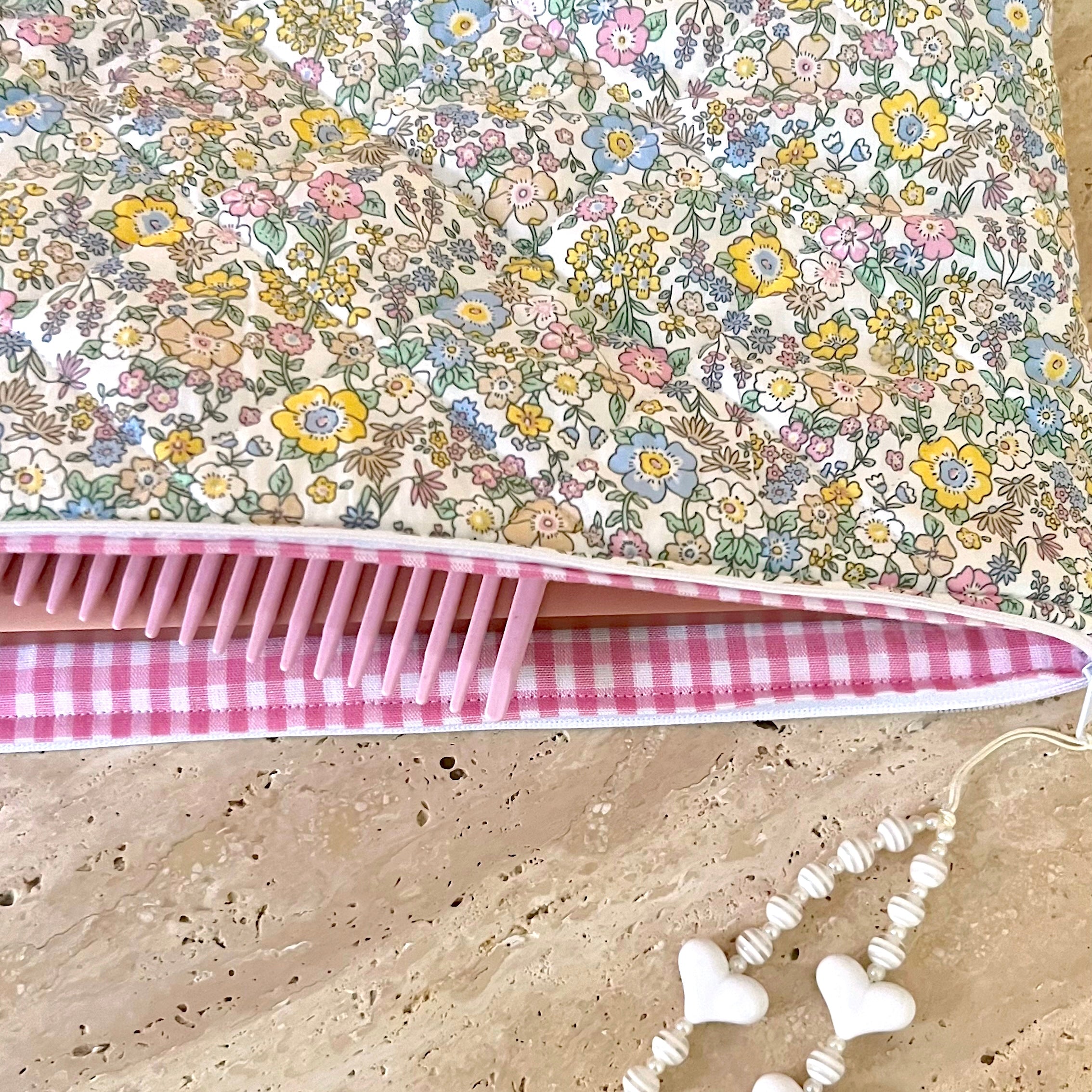 Close-up of floral laptop sleeve with pink comb trim along the opening edge