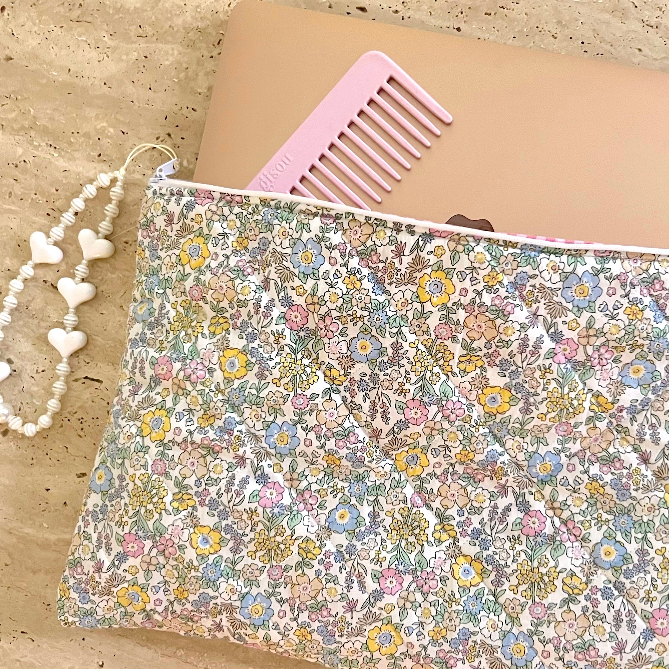 Floral laptop sleeve with pink comb top edge and stitched fabric lining detail