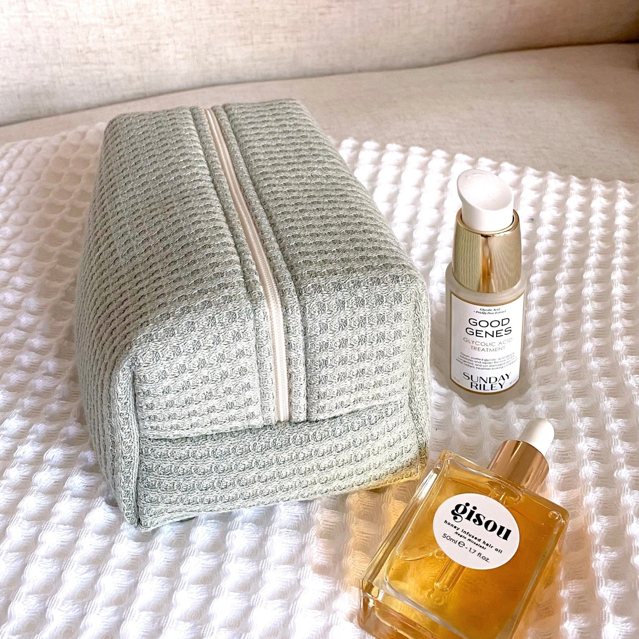 Sage green waffle knit zip pouch with vertical zipper seam and textured fabric.