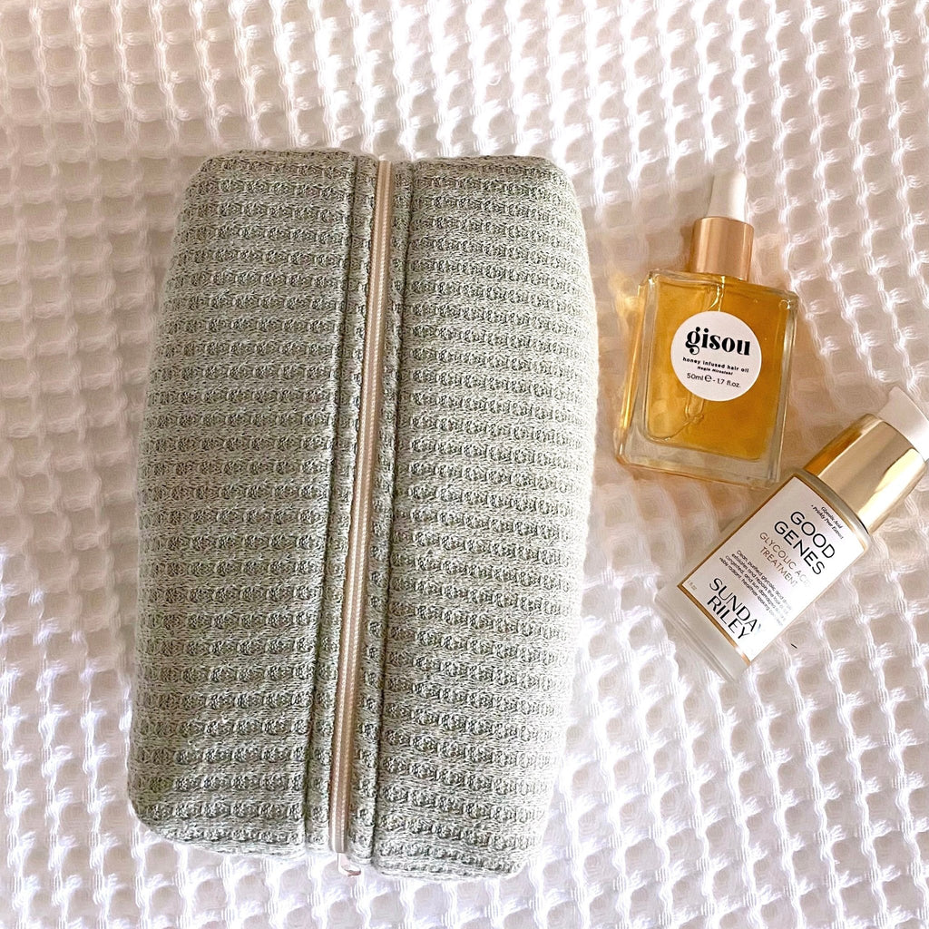 Sage green waffle knit zip pouch with tan zipper tape and textured finish.