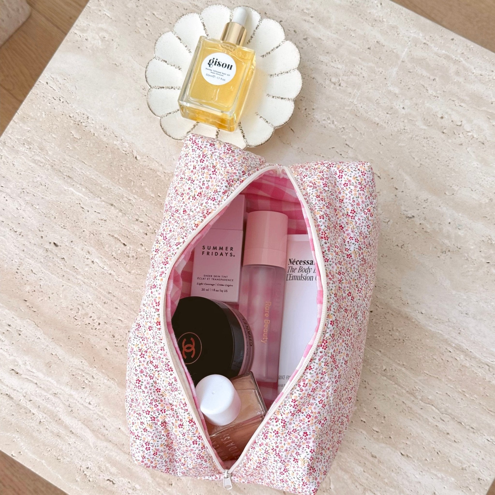 Pink floral zip-top pouch open, pink and cream items visible inside