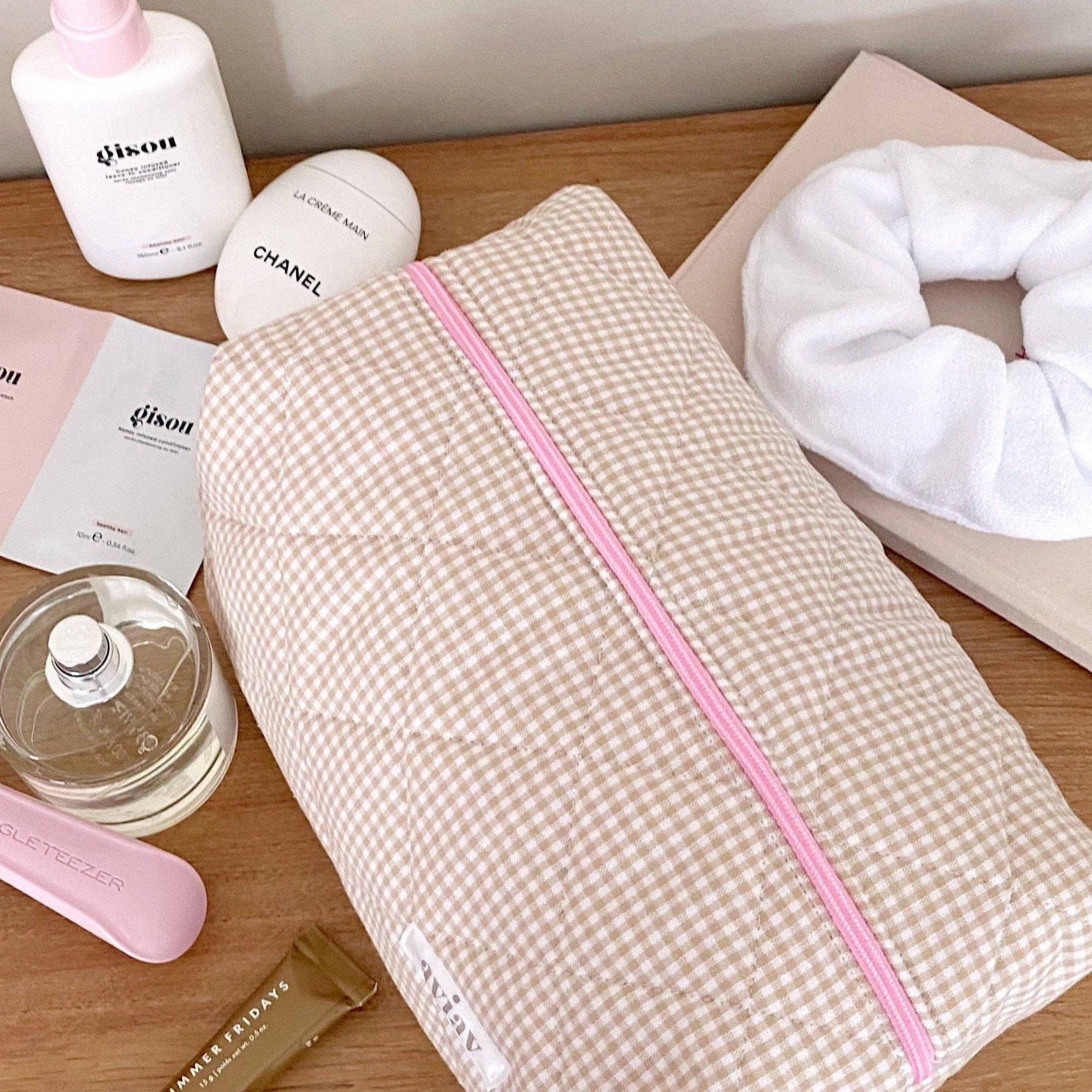 Brown gingham toiletry pouch with pink zipper and piping, angled view