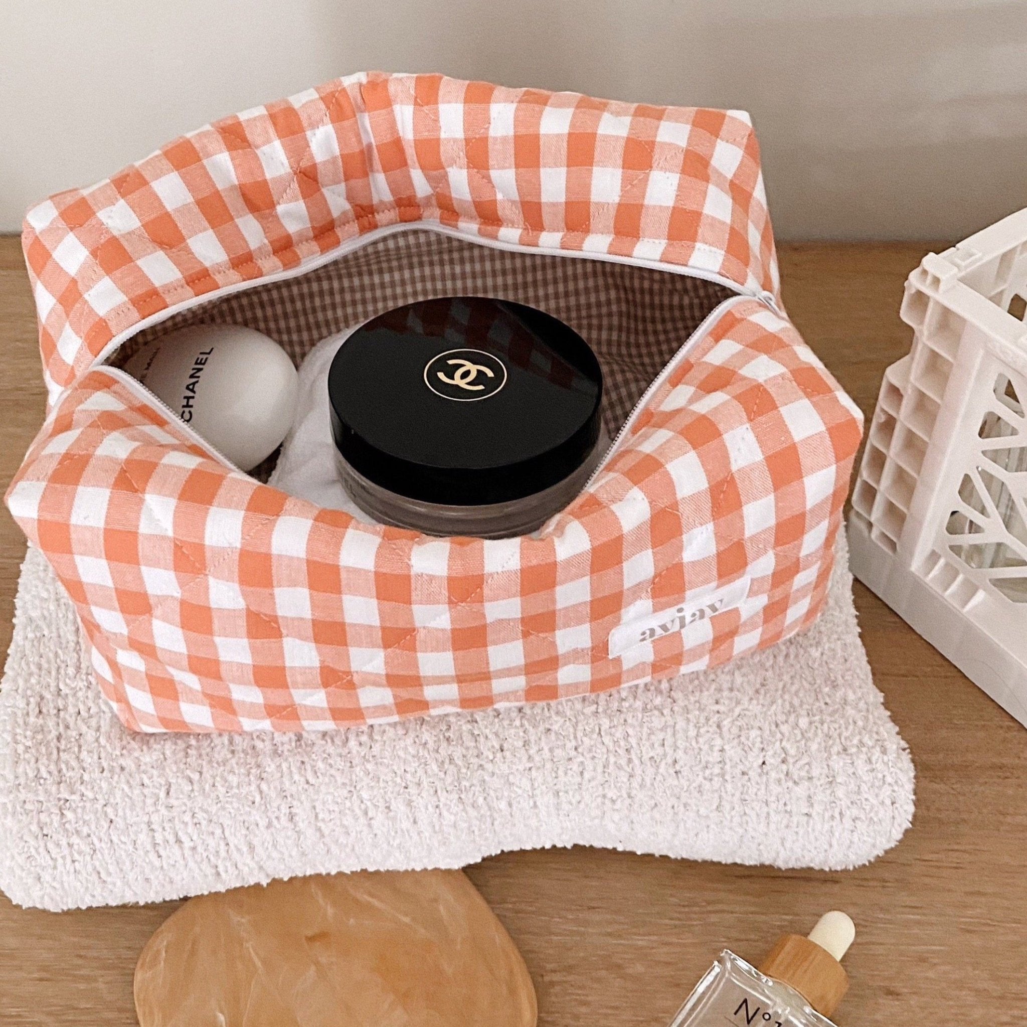 Orange gingham cosmetic pouch open, showing gingham-lined interior and top zipper