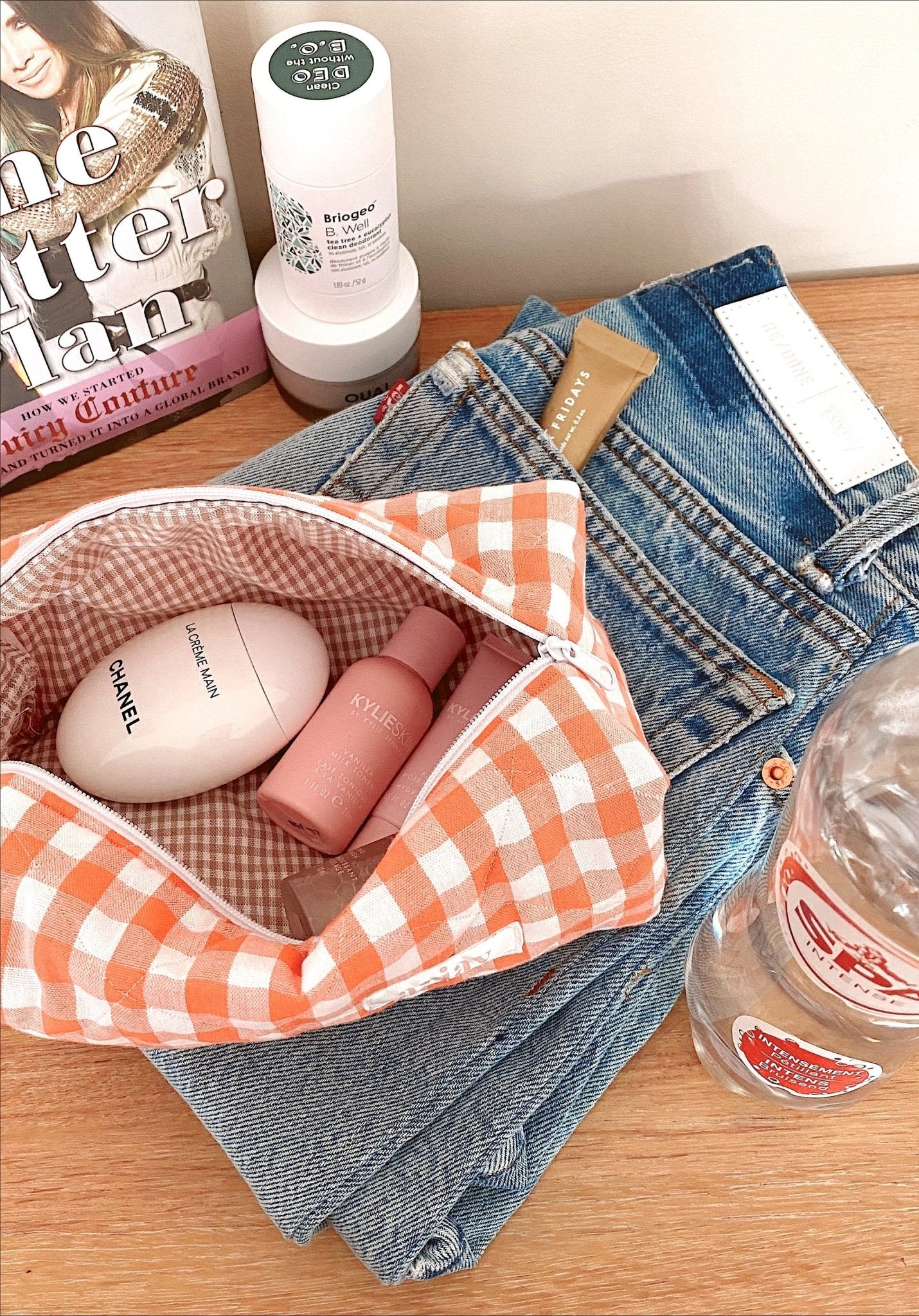Orange gingham pouch open inside denim bag, showing toiletry bottles in gingham lining