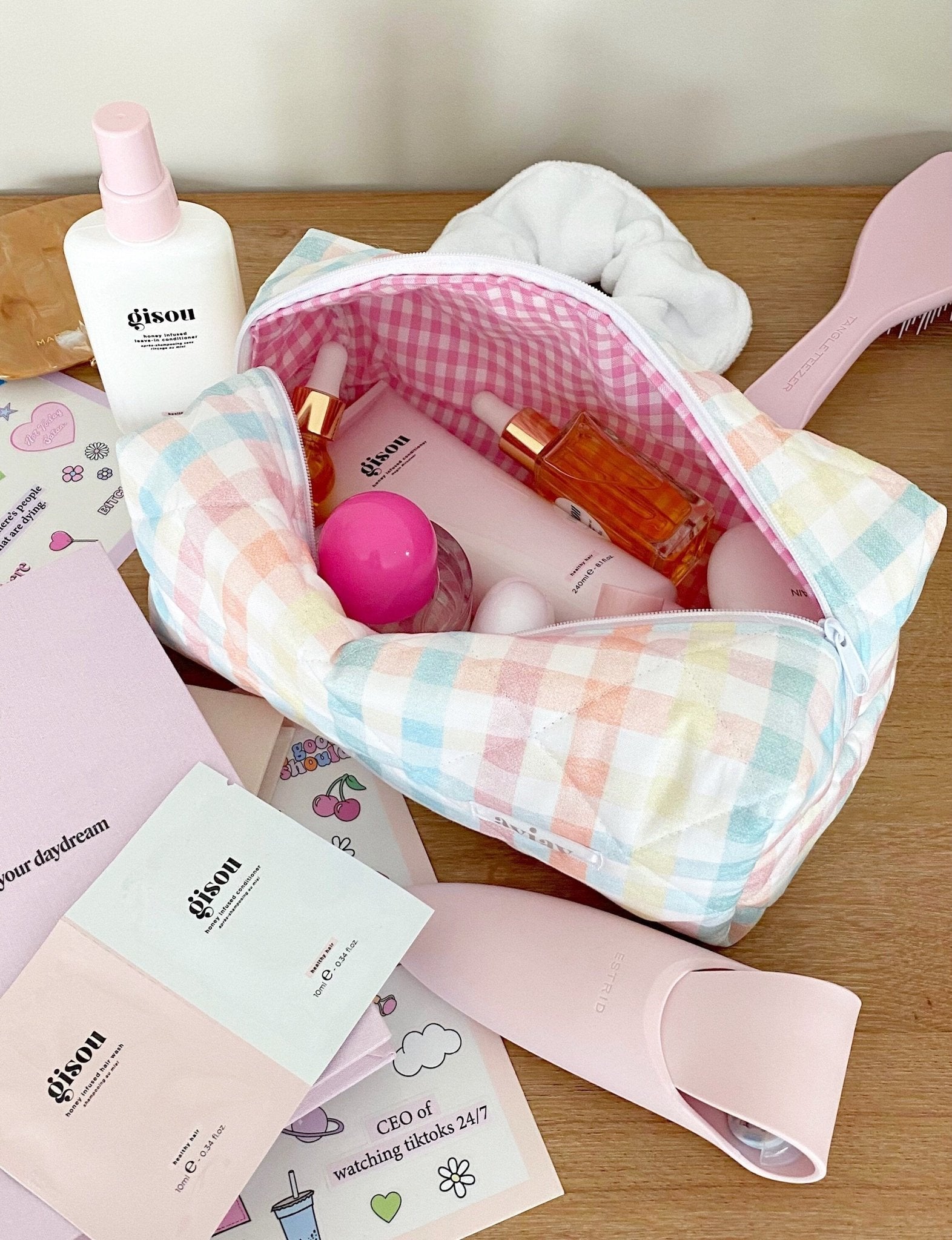 Pastel gingham makeup pouch open with zipper, pink gingham panel and toiletry bottles