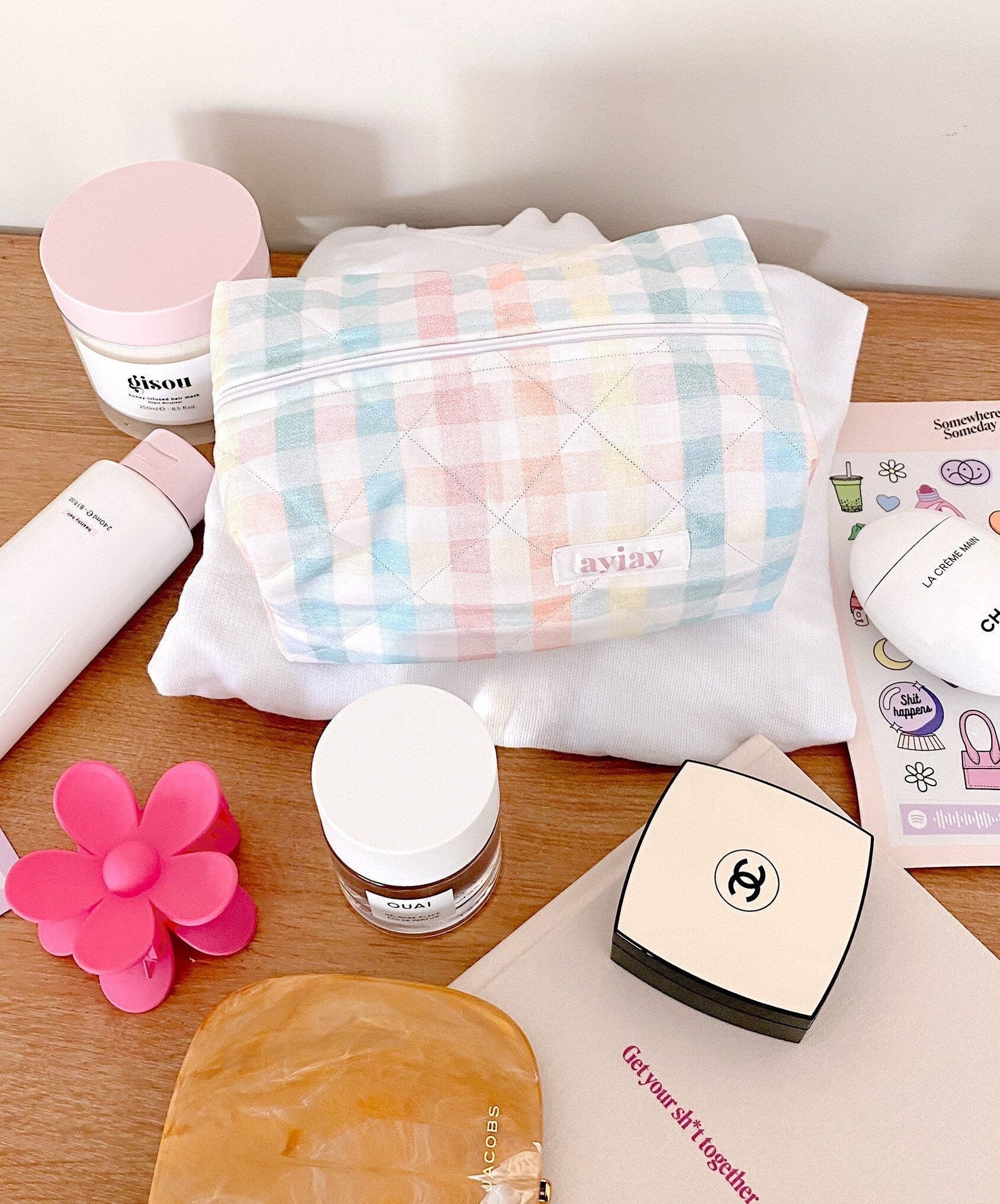 Pastel gingham zip pouch with embroidered logo, folded and lying on a tabletop