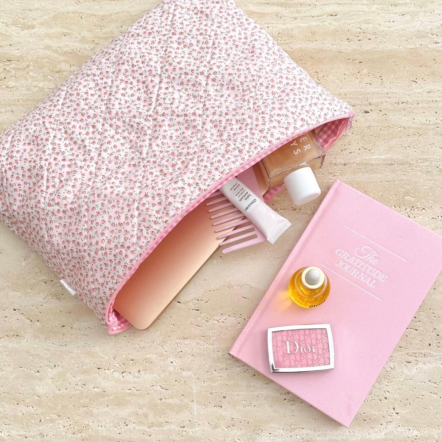 Pink ditsy floral zip cosmetic pouch open, showing brush and small bottles inside