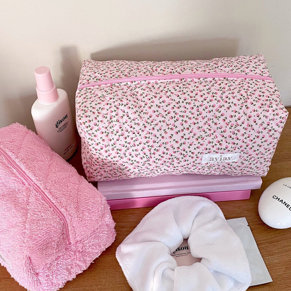 Pink ditsy floral rectangular zip pouch with pink zipper; front logo patch visible.