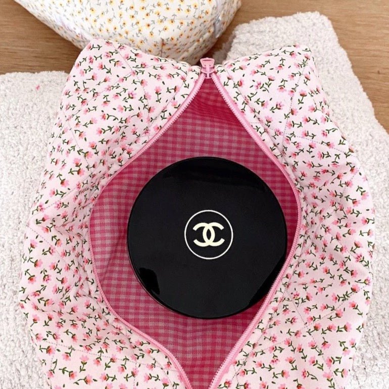 Pink ditsy floral pouch with pink zipper and circular logo pouch insert inside.