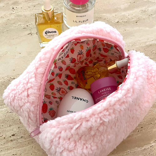 Pink teddy cosmetic bag with strawberry-pattern lining, zippered top, open view.