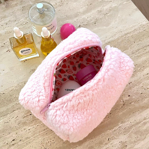 Pink teddy cosmetic pouch with strawberry lining, zip top, partially open.